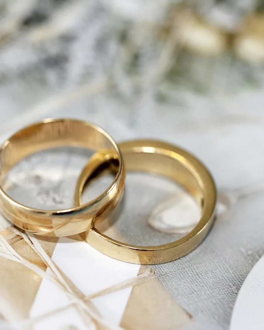 Zwei goldene Eheringe auf hellem Stoff