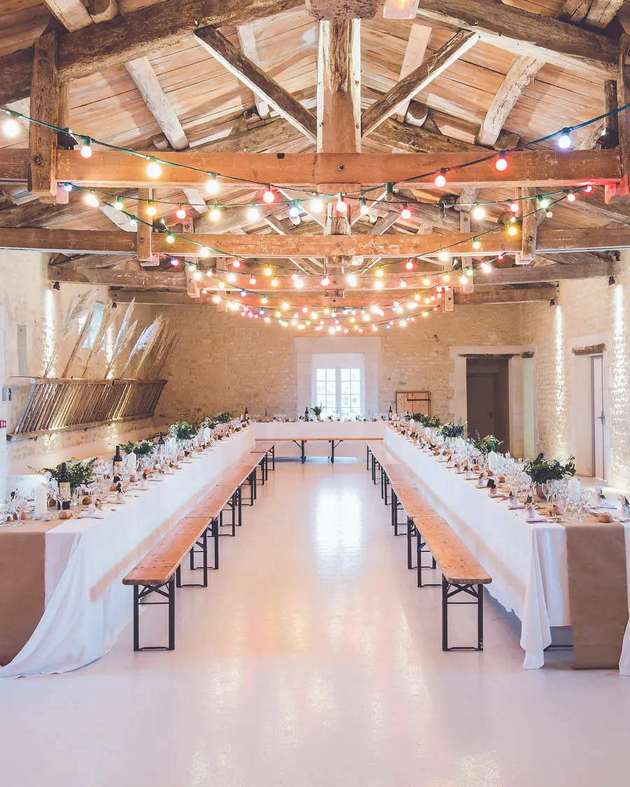 Festsaal mit langen Hochzeitstafeln und Lichterketten