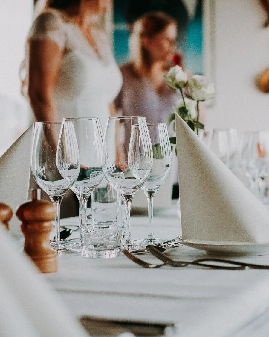Gedeckte Hochzeitstafel mit Weingläsern und weißen Rosen
